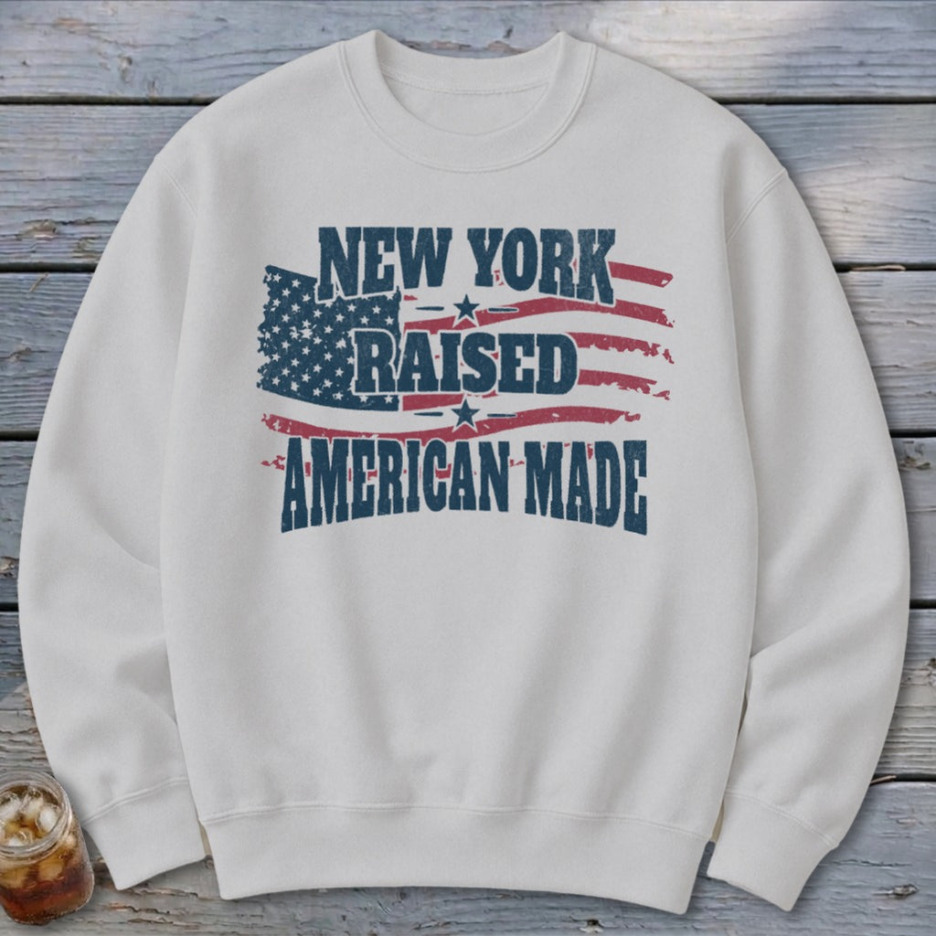 Light gray crewneck sweatshirt featuring distressed patriotic graphics and the text New York Raised American Made.
