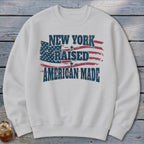 Light gray crewneck sweatshirt featuring distressed patriotic graphics and the text New York Raised American Made.