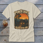 T-shirt with a cabin scene at sunset and text: The Porch Light is Always On.