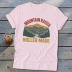 Light pink t-shirt with rolled sleeves featuring a retro mountain graphic and text reading MOUNTAIN RAISED HOLLER MADE.