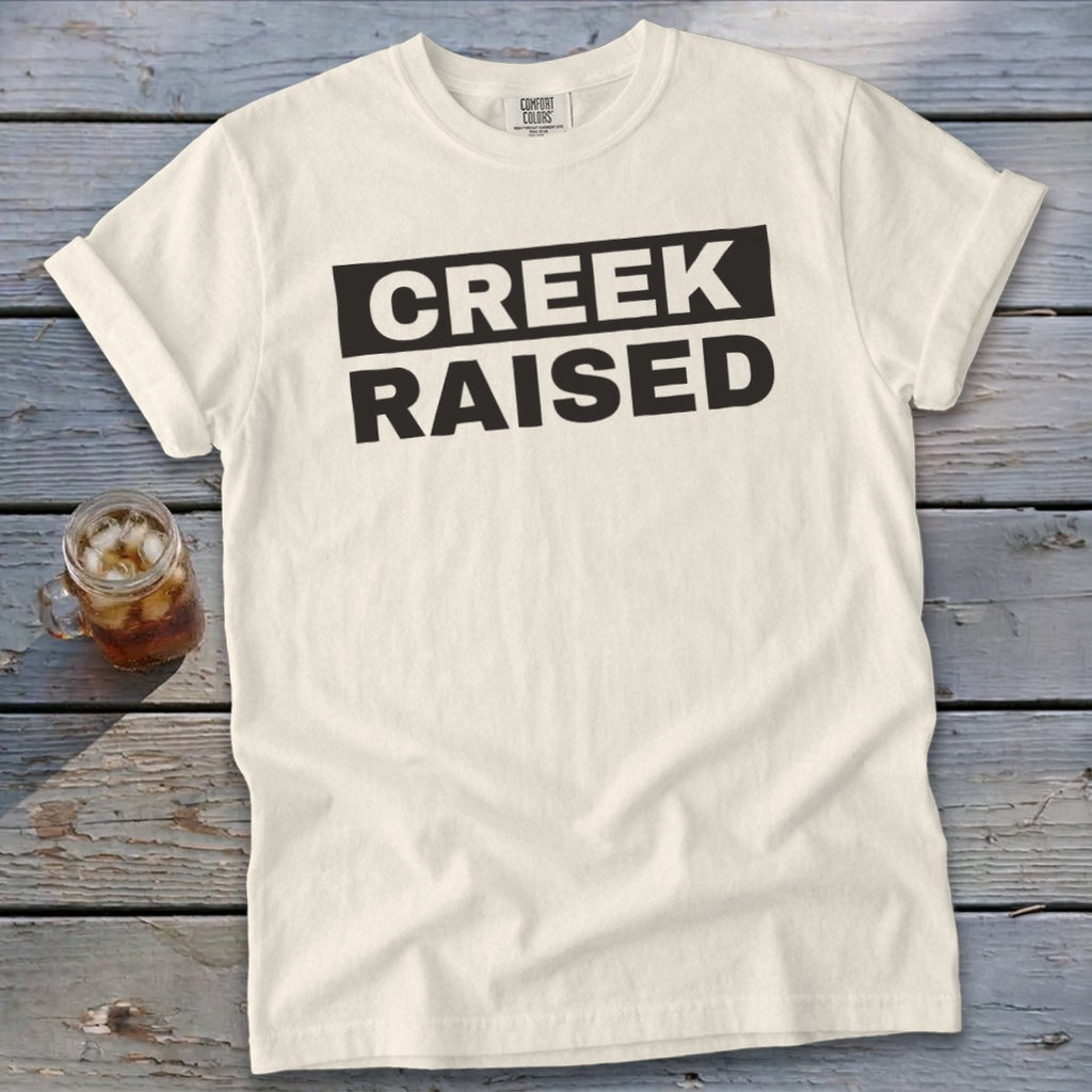 Cream t-shirt with bold black text "CREEK RAISED".
