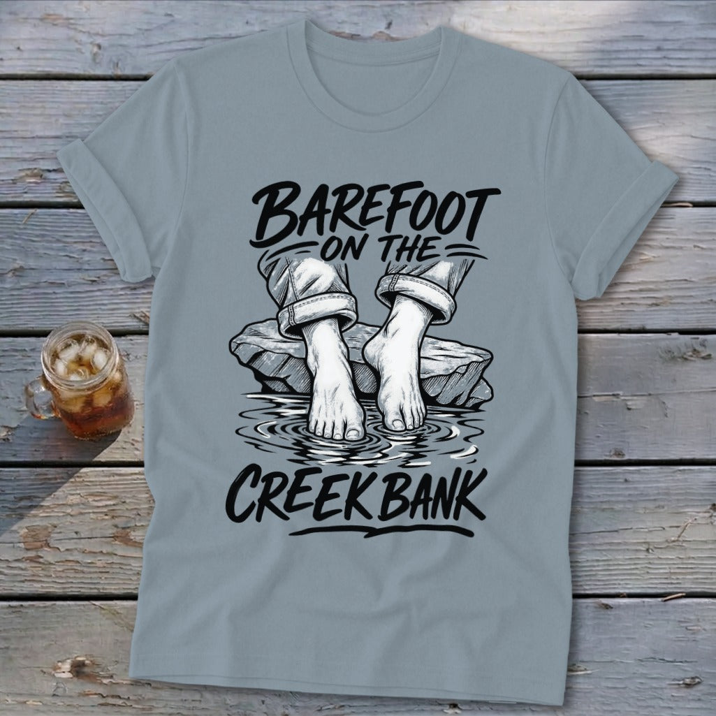 T-shirt with black text "BAREFOOT ON THE CREEK BANK" and illustration of bare feet.