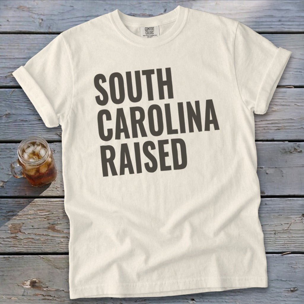 Cream t-shirt with "South Carolina Raised" printed in dark gray text.