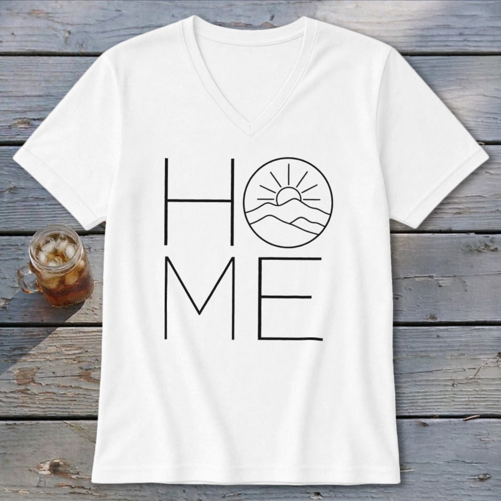 White V-neck t-shirt with black HOME graphic featuring a mountain and sun design on wooden surface.
