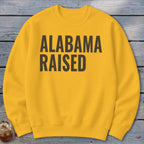 Yellow crewneck sweatshirt with "Alabama Raised" text in dark brown.