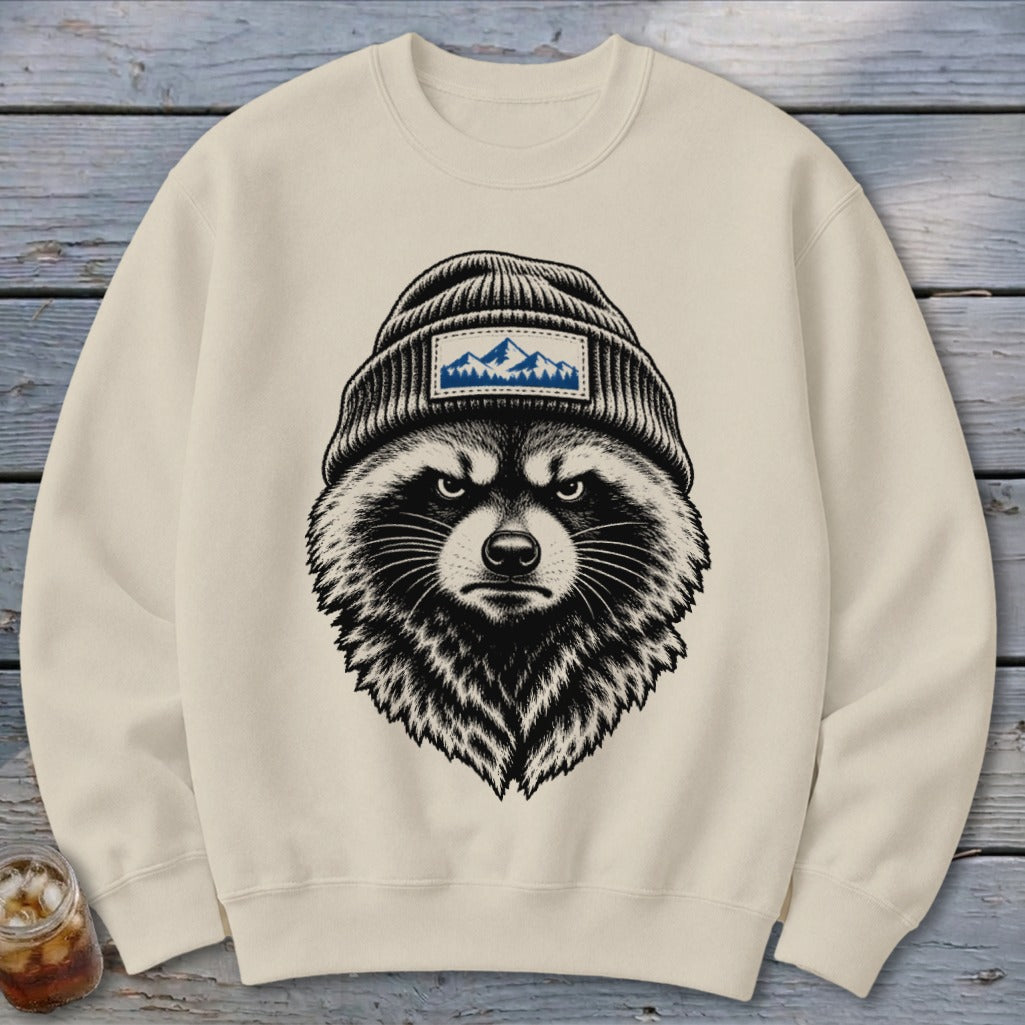 Cream sweatshirt featuring a black and white illustration of a raccoon wearing a beanie with a mountain patch.