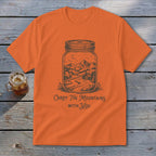 Orange crewneck t-shirt featuring a mason jar graphic containing a mountain scene with text reading Carry The Mountains With You.