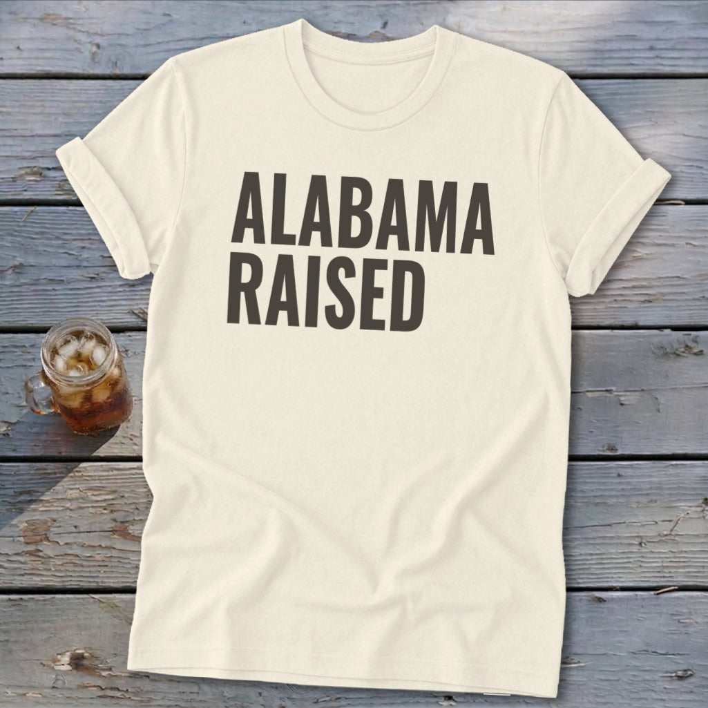 Cream t-shirt with black text reading "ALABAMA RAISED".