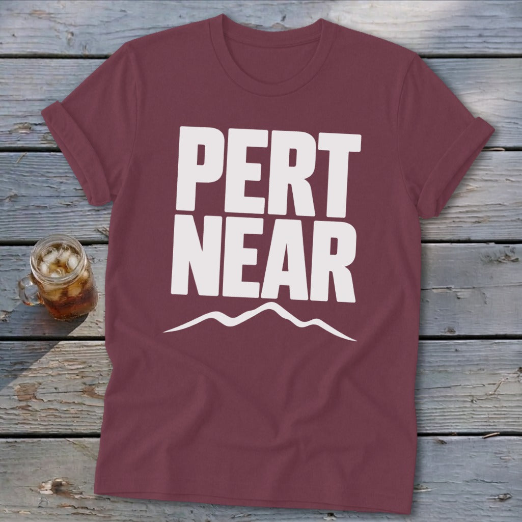 Maroon crewneck t-shirt with short sleeves featuring bold white text that reads PERT NEAR above a mountain outline.