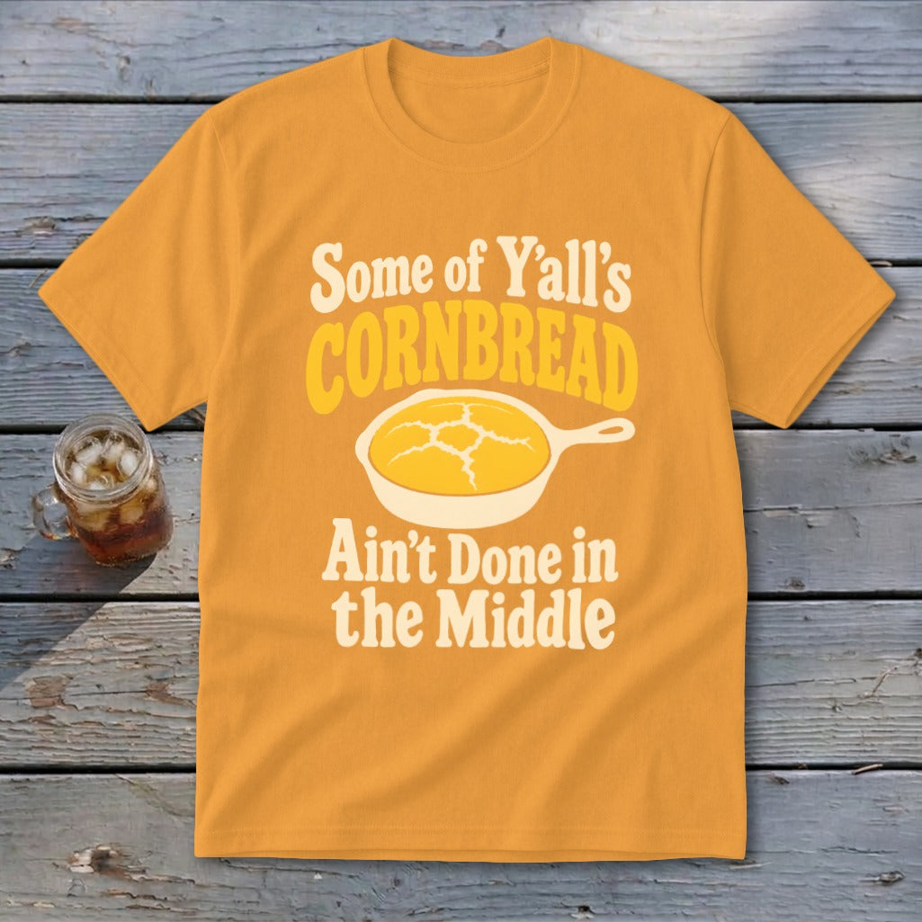 Gold t-shirt featuring a graphic of cornbread in a skillet with the text Some of Yall Cornbread Aint Done in the Middle