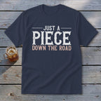 Navy t-shirt with "JUST A PIECE DOWN THE ROAD" graphic.