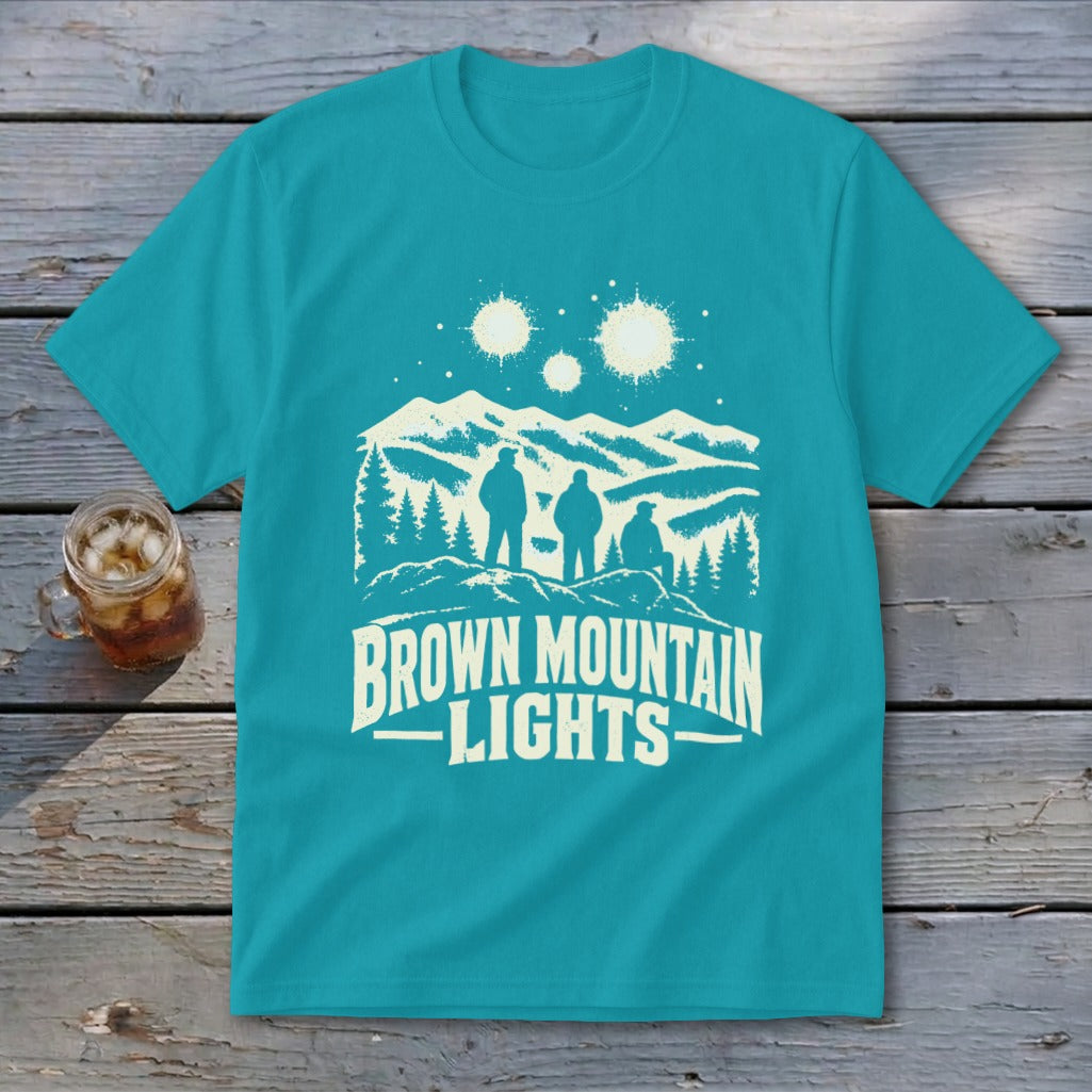 Teal t-shirt featuring a white graphic of three figures, mountains, glowing orbs, and text reading BROWN MOUNTAIN LIGHTS.