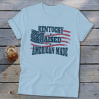 Light blue t-shirt with distressed American flag graphic and text: Kentucky Raised American Made.