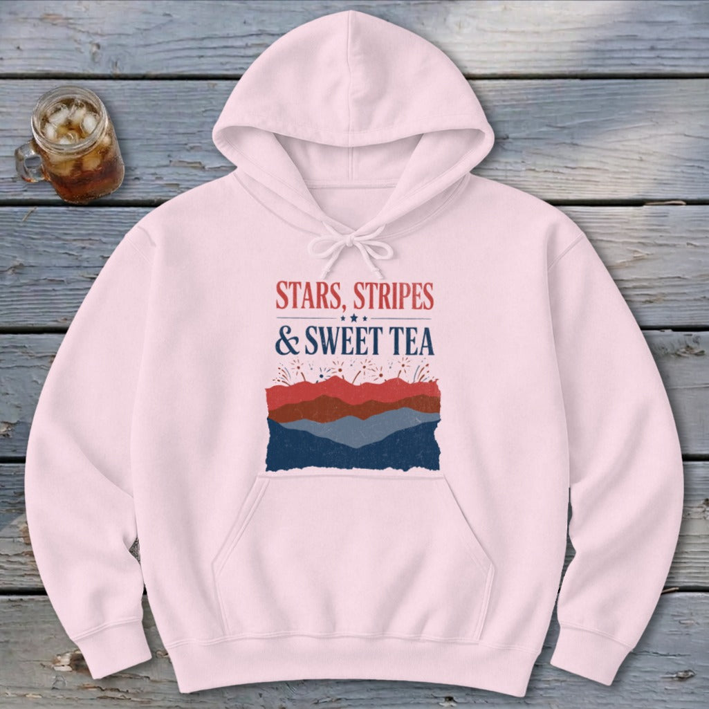 A light pink pullover hoodie featuring the red and blue text Stars, Stripes & Sweet Tea above layered red and blue stylized hills.