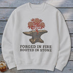 White sweatshirt with an anvil, flowering tree, and text "FORGED IN FIRE ROOTED IN STONE."