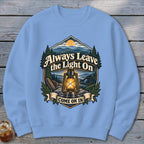 Light blue sweatshirt with a landscape design featuring a lantern and text "Always Leave the Light On COME ON IN".
