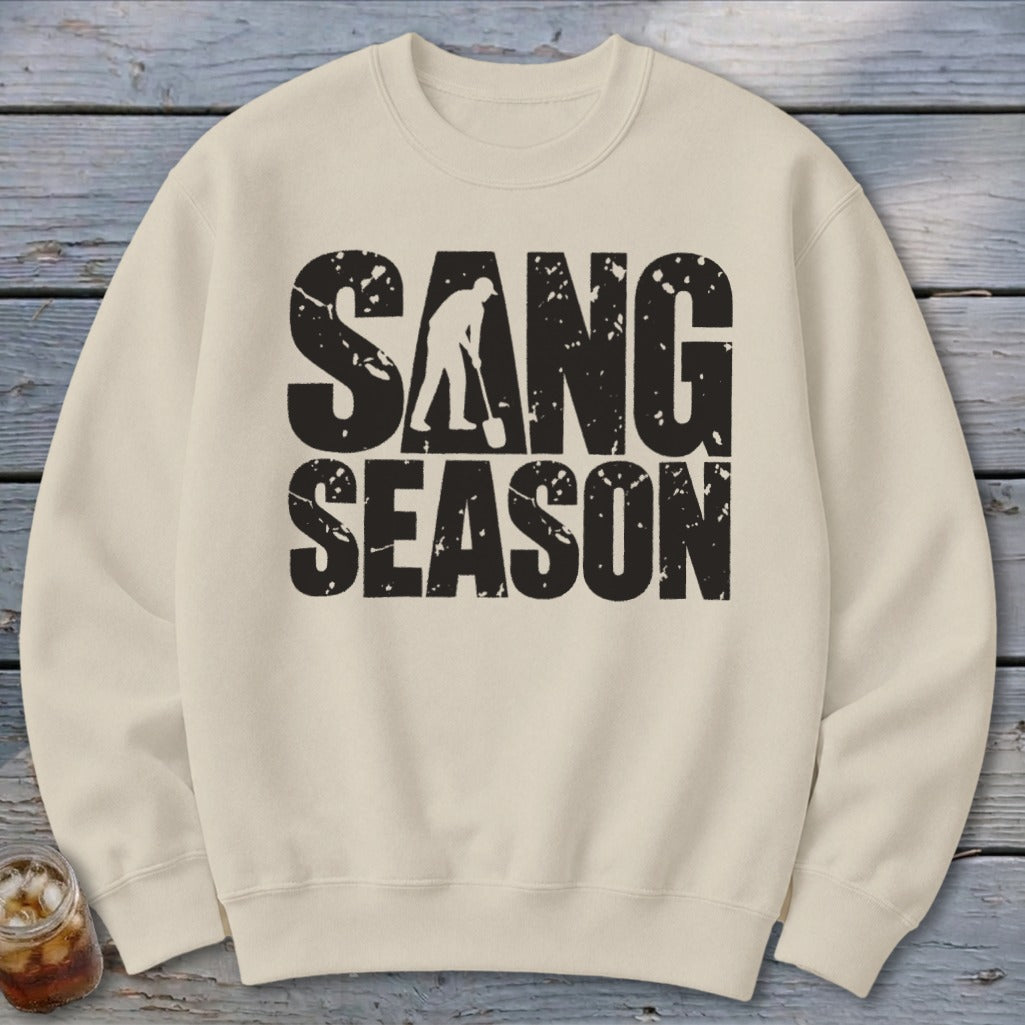 A cream crewneck sweatshirt featuring a distressed black graphic with the text SANG SEASON.
