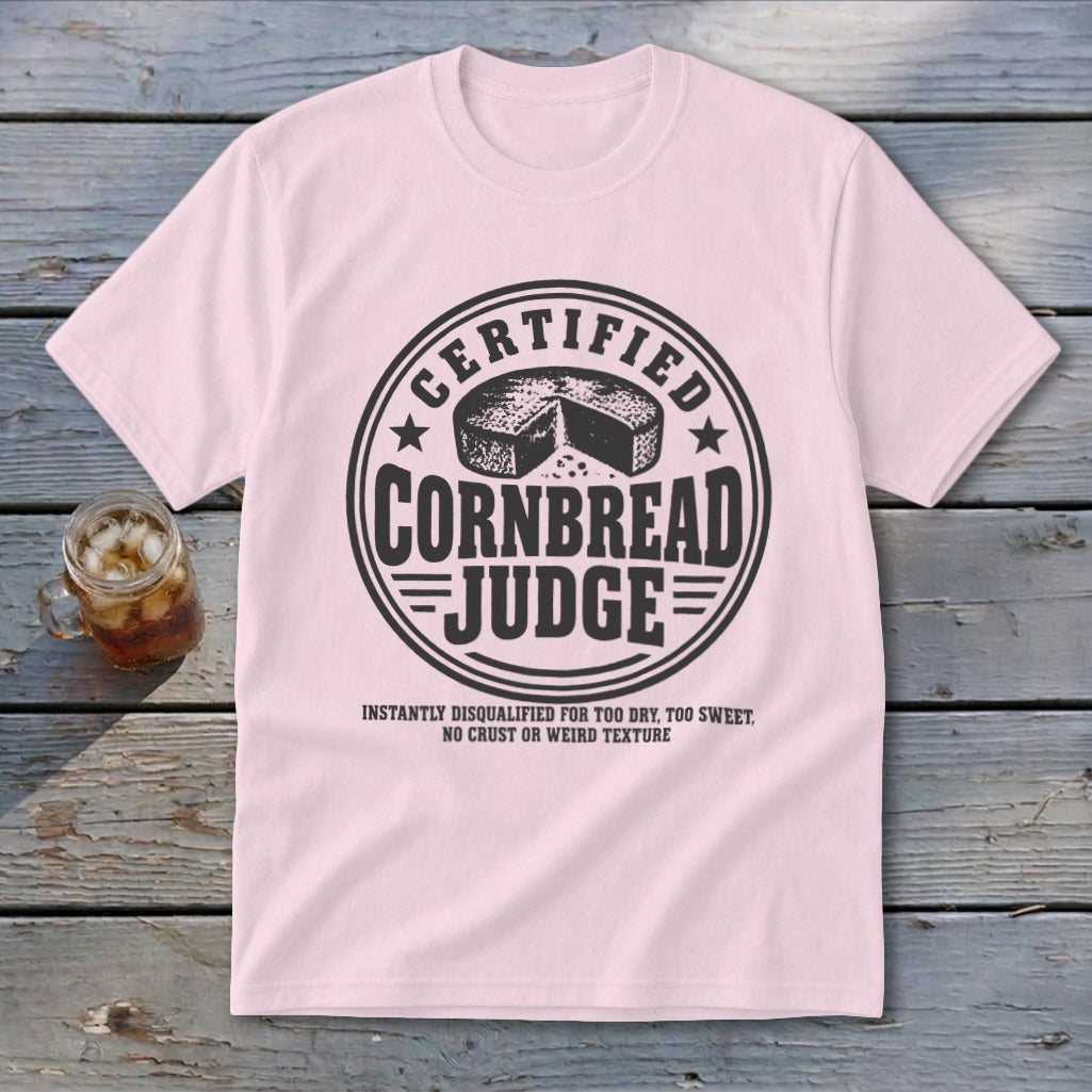 Light pink t-shirt with a black graphic reading "Certified Cornbread Judge" and an illustration of cornbread.