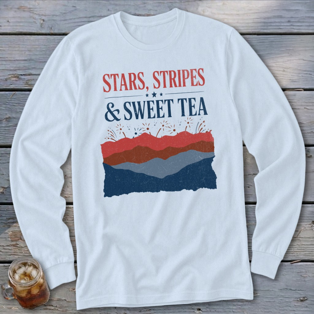 White long-sleeve t-shirt with red and blue graphic text reading Stars, Stripes & Sweet Tea above abstract mountains and fireworks.