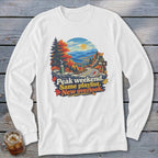 White long-sleeve shirt with mountain landscape graphic and text "Peak weekend. Same playlist. New overlook."