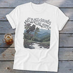 White t-shirt with a bird on a branch overlooking a mountain stream. Text reads "No Place Sounds Like Home."