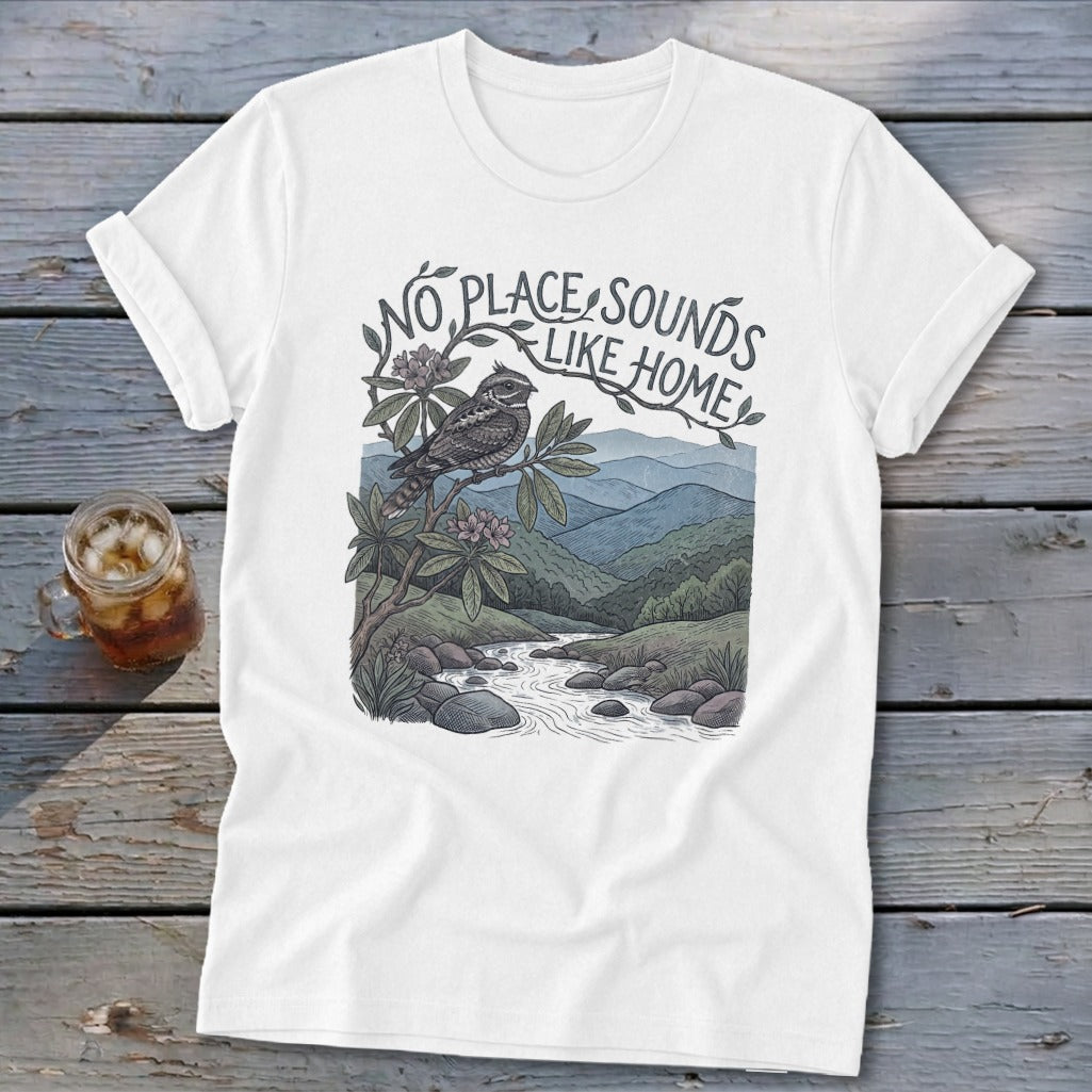 White t-shirt with a bird on a branch overlooking a mountain stream. Text reads "No Place Sounds Like Home."