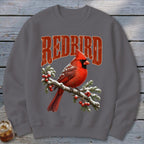 A dark gray crewneck sweatshirt featuring a red cardinal on a snowy branch and the text Redbird.