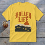 A yellow t-shirt with the orange text "HOLLER LIFE" above a sunset landscape.