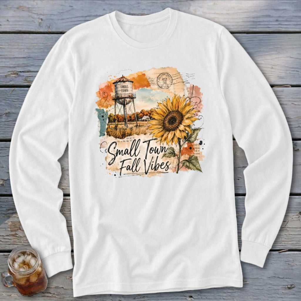 White long sleeve shirt with "Small Town Fall Vibes" graphic featuring a sunflower and water tower.