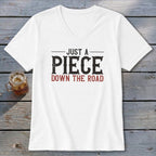 White v-neck t-shirt with distressed text that reads "JUST A PIECE DOWN THE ROAD".