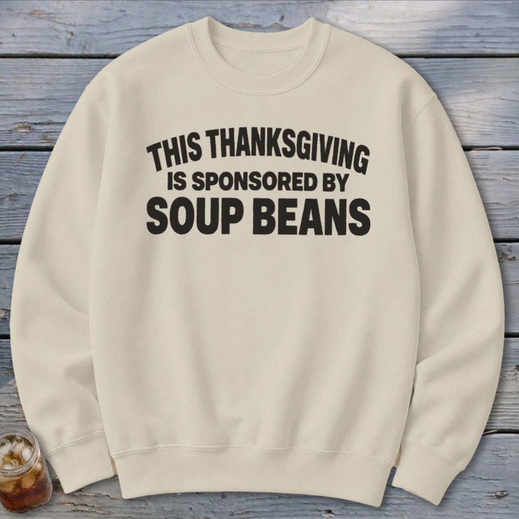 A cream-colored crewneck sweatshirt printed with the black text THIS THANKSGIVING IS SPONSORED BY SOUP BEANS.
