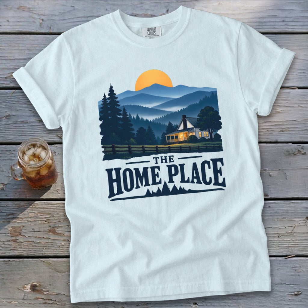 White t-shirt with "The Home Place" text over a landscape of a house and mountains.