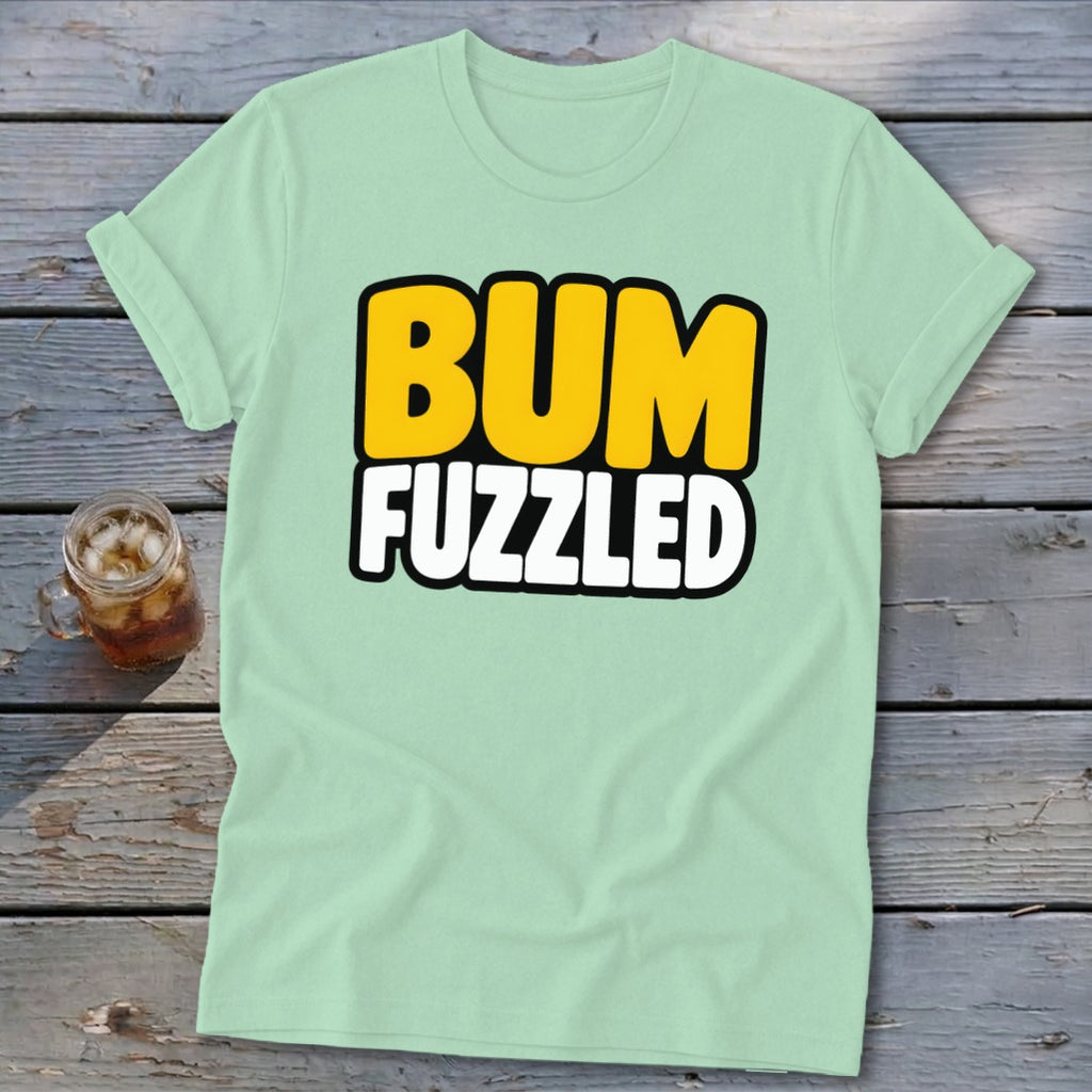 A mint green short-sleeve t-shirt with the text BUM FUZZLED on a wooden surface.