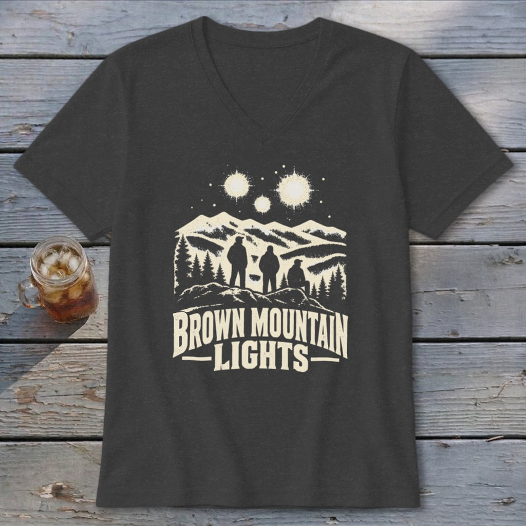 A dark gray V-neck t-shirt featuring a graphic of three figures viewing glowing orbs over mountains and the text "Brown Mountain Lights".