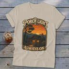T-shirt with graphic of a cabin, sunset, and text "The Porch Light is Always On."
