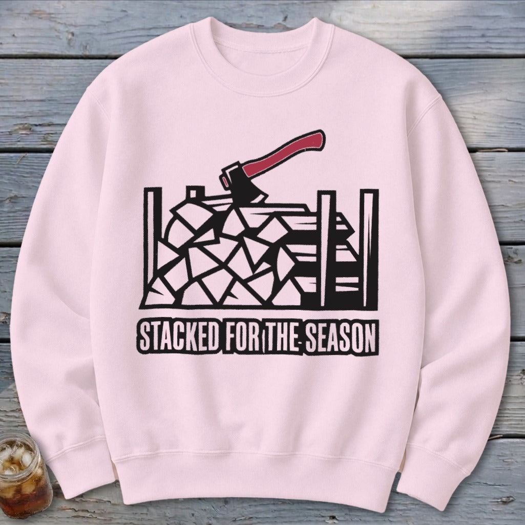 Pink sweatshirt with graphic of stacked firewood, axe, and text "STACKED FOR THE SEASON".