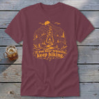 Maroon t-shirt with graphic of mountains, lantern, and text "If you hear whistlin', keep hiking."