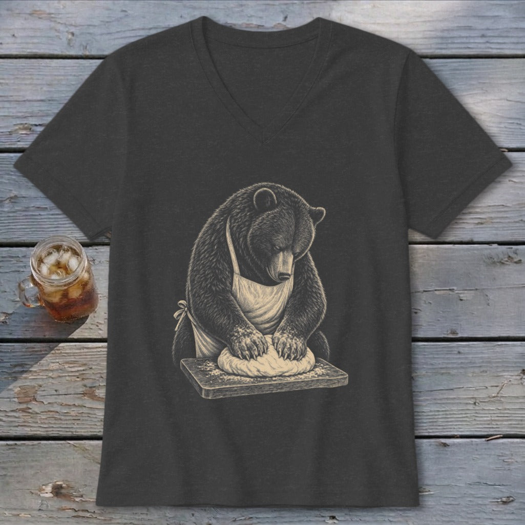 Bear wearing an apron kneading dough on a wooden board.