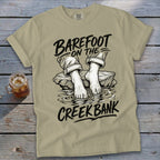 Tan t-shirt with "Barefoot on the Creek Bank" graphic of bare feet in water.