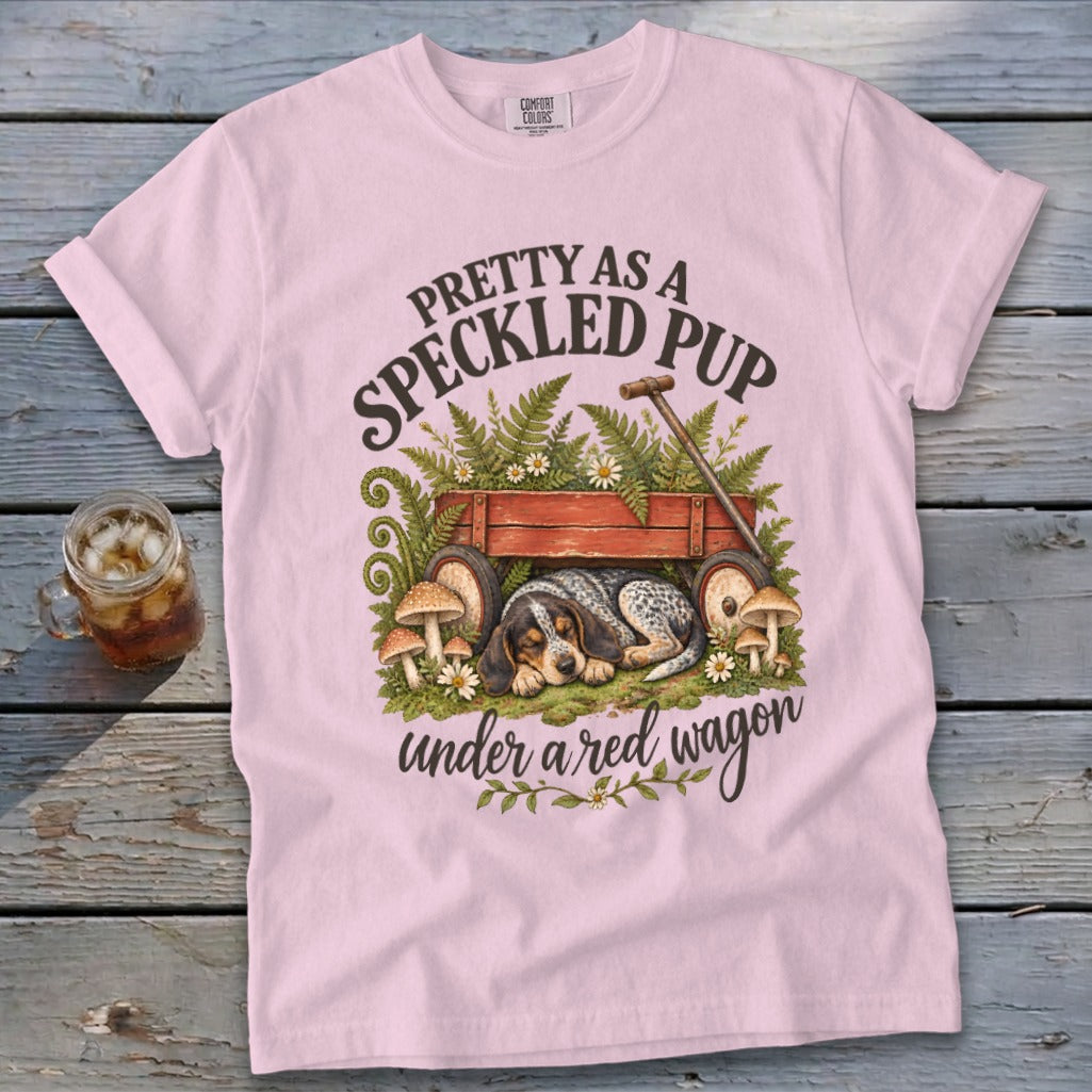 Pink t-shirt with "Pretty as a Speckled Pup Under a Red Wagon" text, dog, wagon, ferns, and mushrooms.