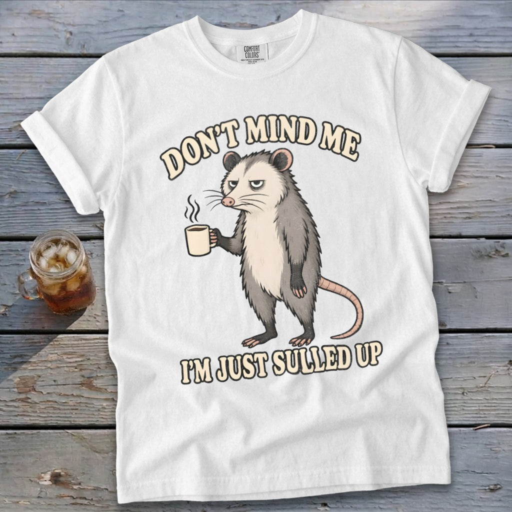 White t-shirt with a grumpy possum holding a coffee mug and text.