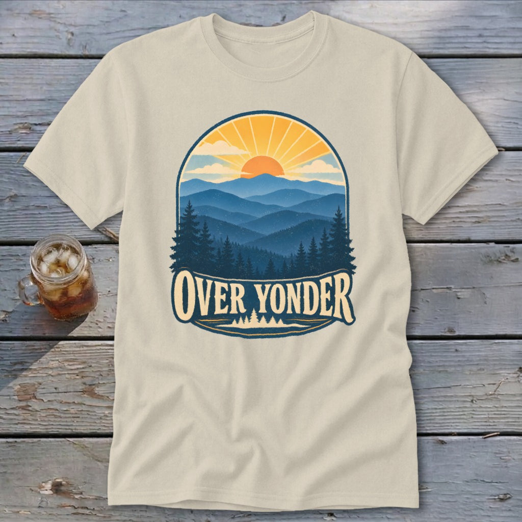 Cream t-shirt featuring a retro mountain landscape graphic with the text Over Yonder, laid on wood.
