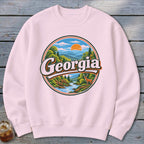 Pink sweatshirt with a circular graphic of a Georgia landscape with a deer.