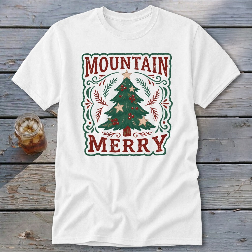A white t-shirt featuring a green and red holiday graphic with a Christmas tree and text reading MOUNTAIN MERRY.