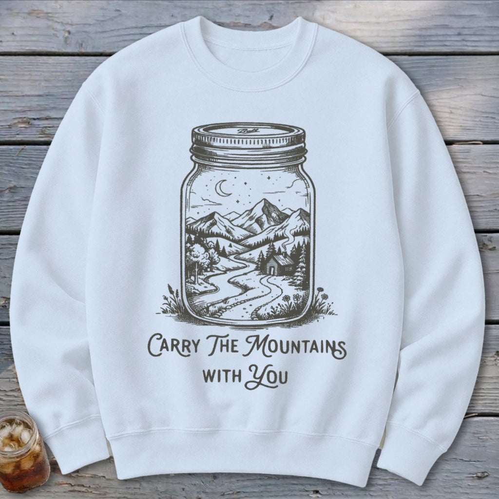 White crewneck sweatshirt featuring a black graphic of a mason jar enclosing a mountain landscape with the text "Carry The Mountains With You."
