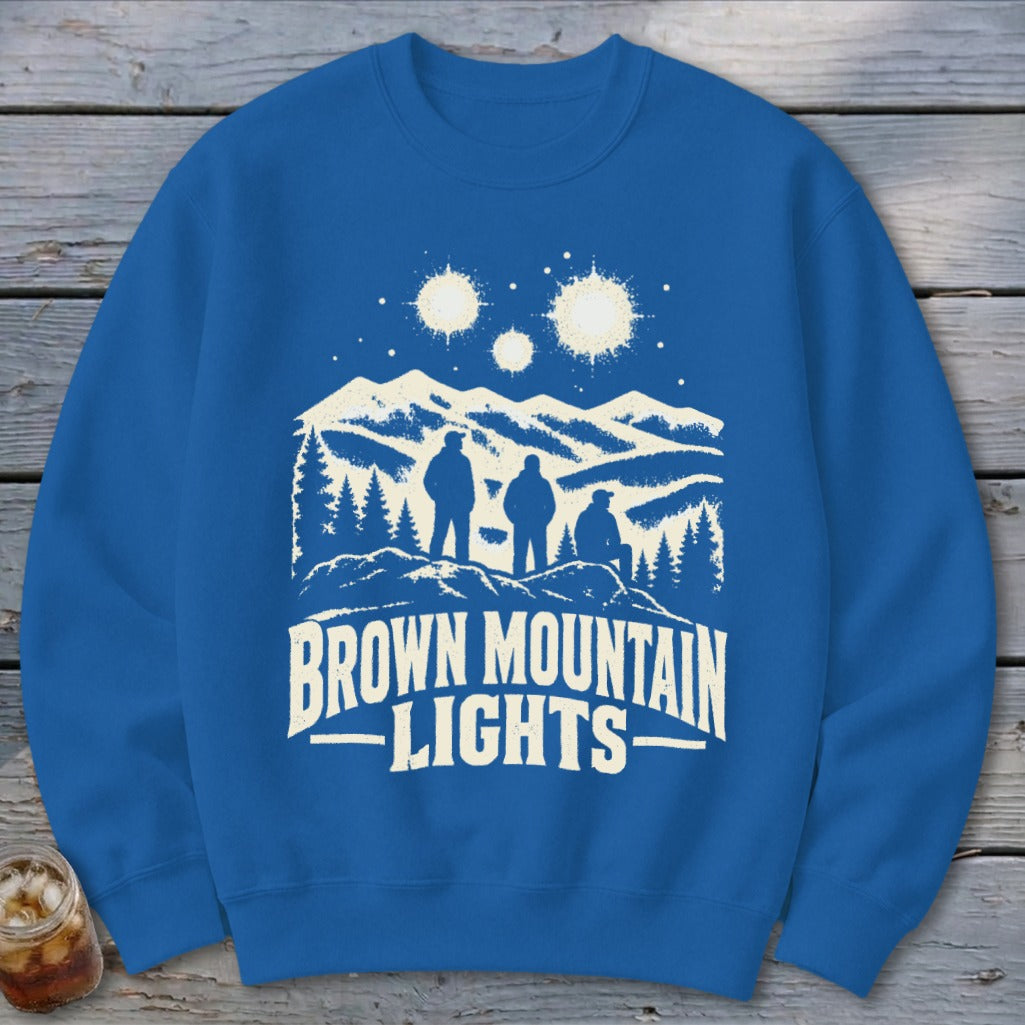 A blue crewneck sweatshirt featuring a graphic of three figures looking at mountain lights.