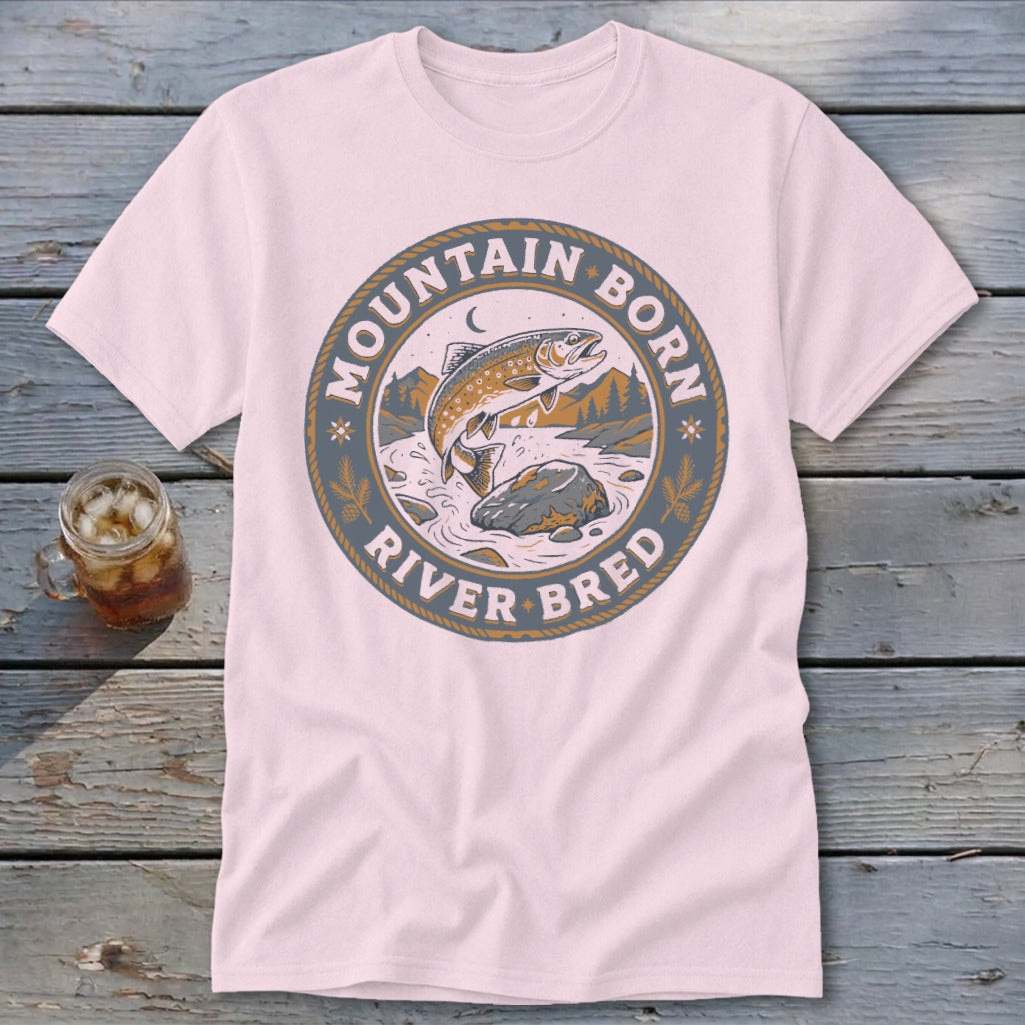 Pink t-shirt with circular graphic of jumping trout, mountains, and text "Mountain Born River Bred".