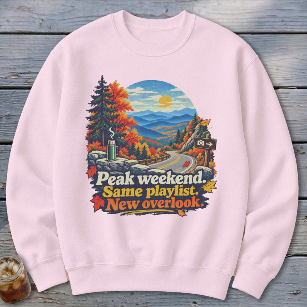 Sweatshirt with mountains, trees, road, and text: Peak weekend. Same playlist. New overlook.