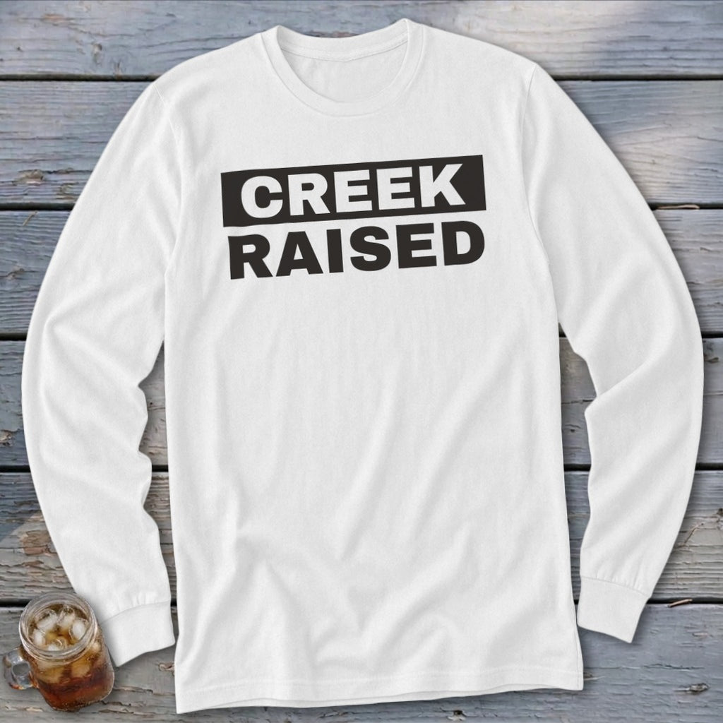 White long-sleeved shirt with black text that says "CREEK RAISED".
