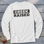 White long-sleeved shirt with black text that says "CREEK RAISED".